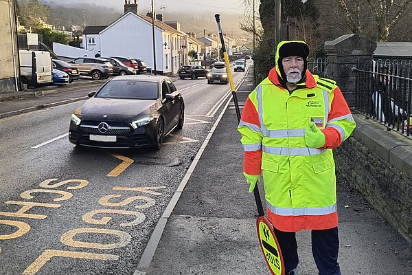 Road crossing patrol person next to a busy main road.